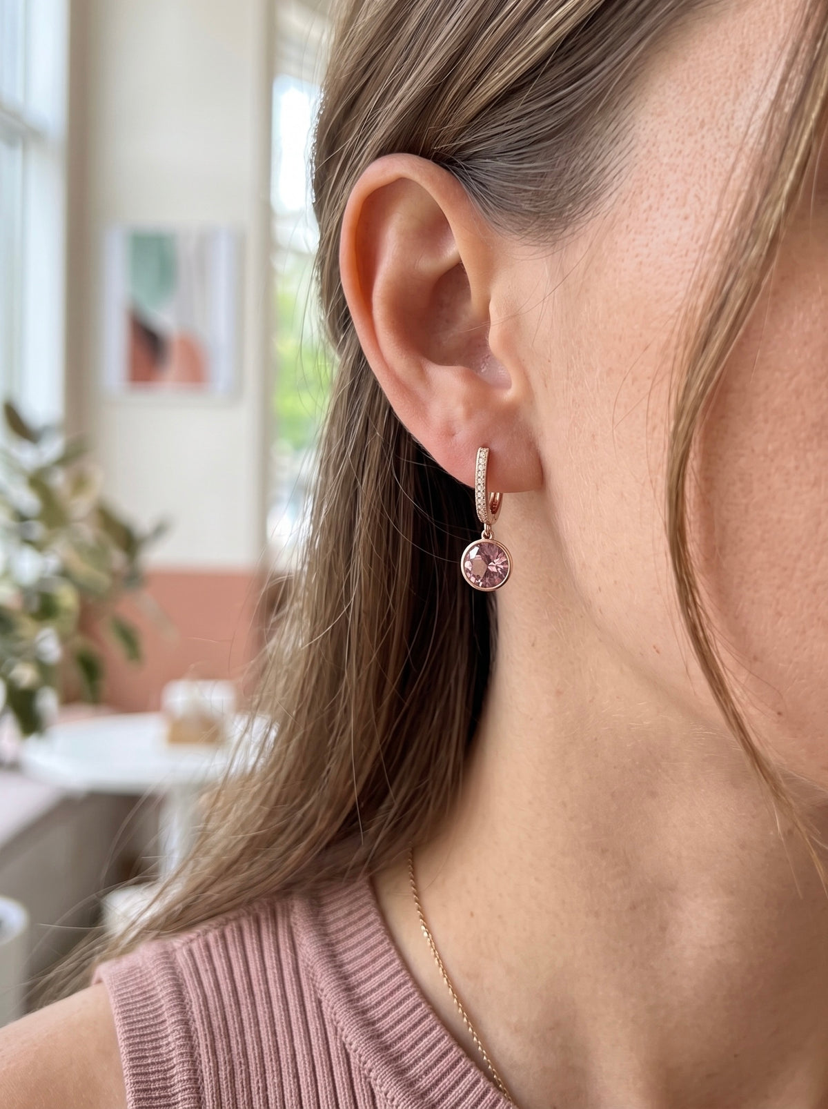 Sieviete ar 18K apzeltītiem auskariem "Merveille", ko rotā liels pūderrozā Swarovski kristāls un smalki cirkoni.