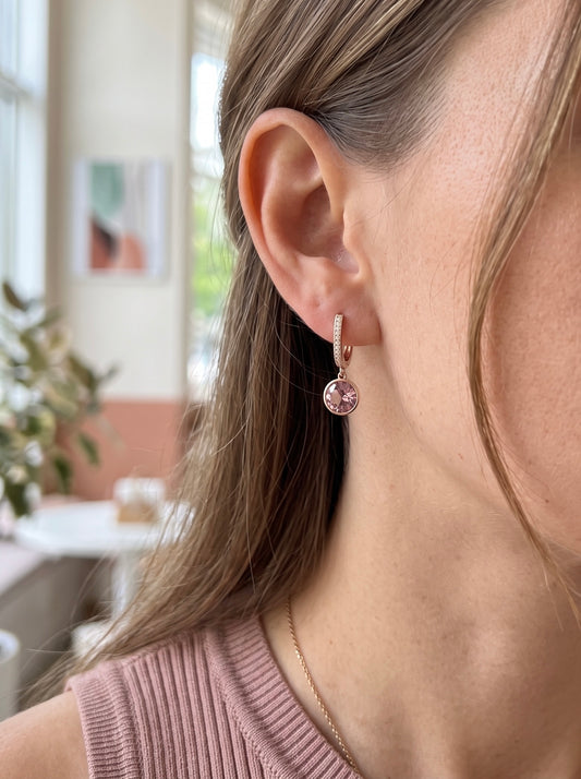 Sieviete ar 18K apzeltītiem auskariem "Merveille", ko rotā liels pūderrozā Swarovski kristāls un smalki cirkoni.